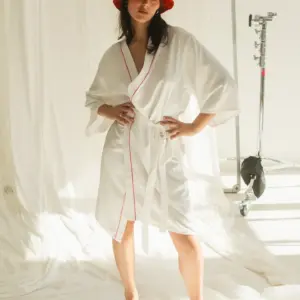 Weißer Satin-Brautkimono mit roten Paspel-Akzenten, vorne geschlossen, Modell zeigt Vorderansicht.